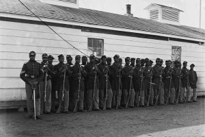 Soldiers of Company E, 4th U.S. Colored Infantry, stand outside at Fort Lincoln, Washington, D.C. (Library of Congress photograph)