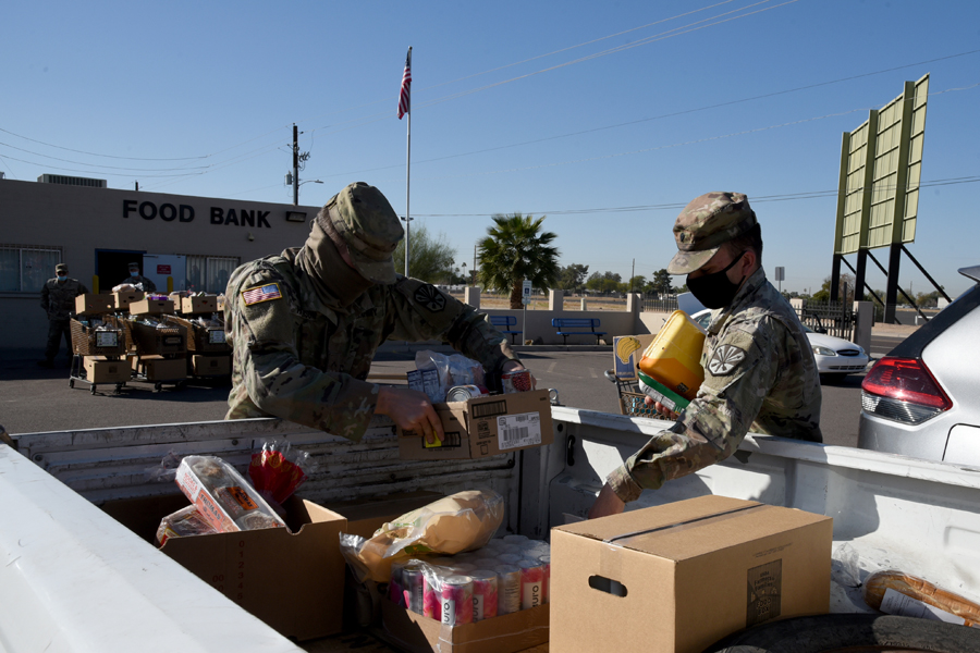 Arizona National Guard Soldiers work alongside civilians filling boxes with groceries and distributing them to local citizens at a food bank in Glendale, Ariz.,