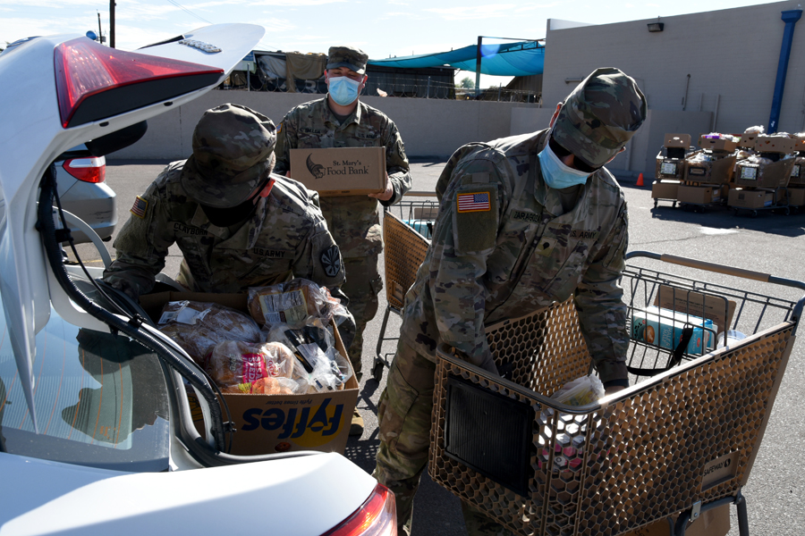 Arizona National Guard Soldiers work alongside civilians filling boxes with groceries and distributing them to local citizens