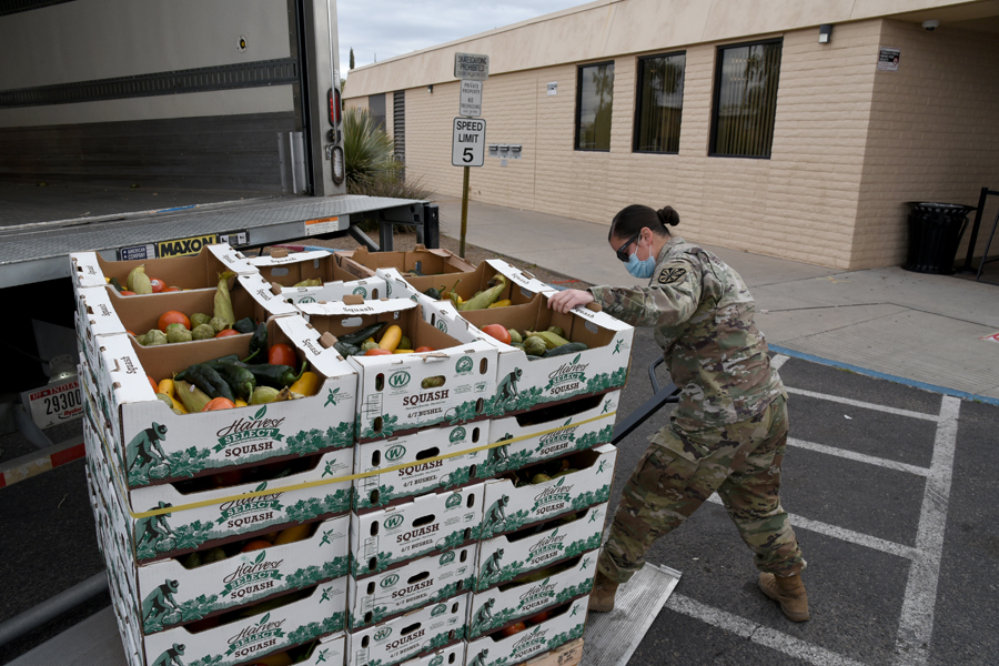 Pfc. Valerie Strong, 2220 Transportation Company, heavy vehicle operator, unloads boxes of produce at a Tucson, Ariz.