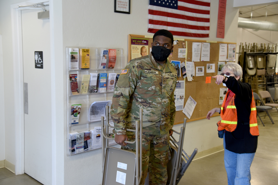 Private 1st Class Theron Johnson, 1-158th Infantry Battalion, combat medic, helps set up a COVID-19 vaccination site