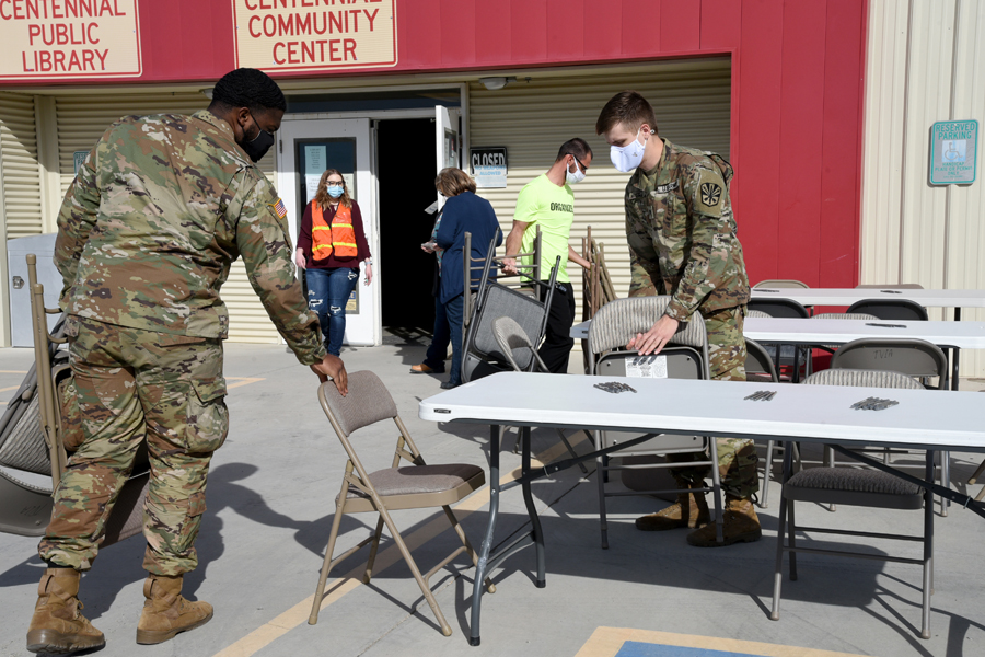 Private 1st Class Theron Johnson, 1-158th Infantry Battalion, combat medic, and Spc. Justin Myers, 996 Area Support Medical Company, combat medic, help set up a COVID-19 vaccination site