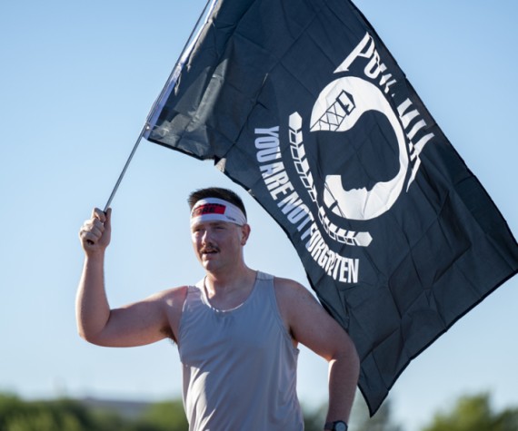 U.S. Air Force Staff Sgt. John Alex Sundell, 355th Equipment Maintenance Squadron aircraft ground equipment craftsman, carries the POW/MIA flag during a 5k held at Davis-Monthan Air Force Base, Arizona, Sept. 16, 2022. The 355th Wing along with the Air Force Sergeants Association, Chapter 1261, held a POW/MIA Remembrance 5k to honor and remember the sacrifices made by those who were prisoners of war and missing in action. (U.S. Air Force photo by Staff Sgt. Kristine Legate)