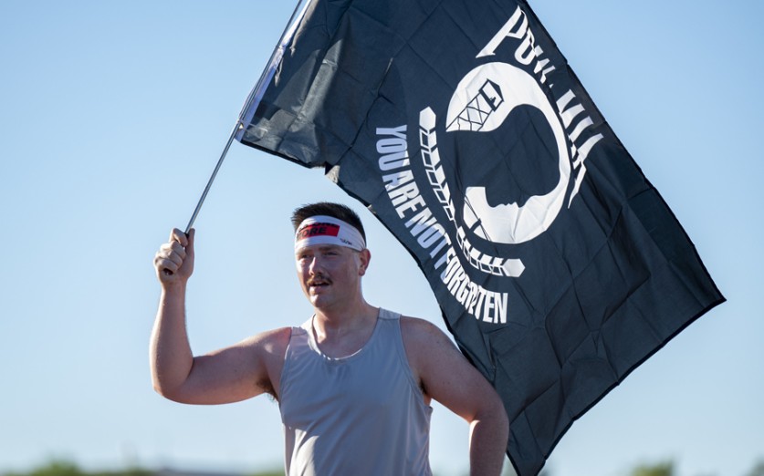 U.S. Air Force Staff Sgt. John Alex Sundell, 355th Equipment Maintenance Squadron aircraft ground equipment craftsman, carries the POW/MIA flag during a 5k held at Davis-Monthan Air Force Base, Arizona, Sept. 16, 2022. The 355th Wing along with the Air Force Sergeants Association, Chapter 1261, held a POW/MIA Remembrance 5k to honor and remember the sacrifices made by those who were prisoners of war and missing in action. (U.S. Air Force photo by Staff Sgt. Kristine Legate)