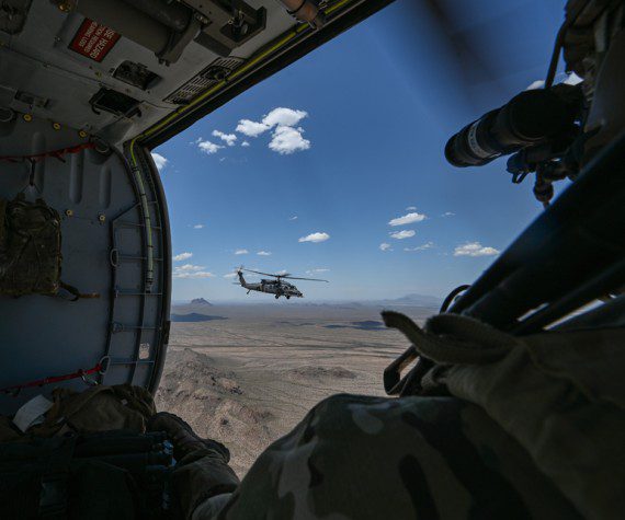 A U.S. Air Force Airman watches an HH-60W Jolly Green II helicopter, assigned to Kirtland Air Force Base, N.M., fly during Red Flag-Rescue 23-1 over Arizona, May 13, 2023. During this iteration of RF-R, Airmen from across the country, as well as Marines, Soldiers and Sailors worked together to complete multiple training exercises and build joint force relationships.