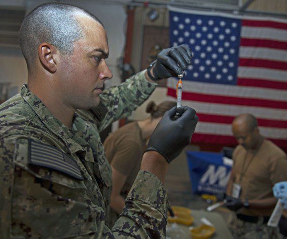 Navy Petty Officer 3rd Class Bryan Reed, assigned to Michaud Expeditionary Medical Facility, prepares supplies for COVID-19 vaccines. Navy photograph by PO1 Jacob Sippel