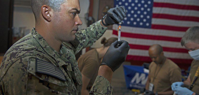 Navy Petty Officer 3rd Class Bryan Reed, assigned to Michaud Expeditionary Medical Facility, prepares supplies for COVID-19 vaccines. Navy photograph by PO1 Jacob Sippel