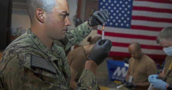 Navy Petty Officer 3rd Class Bryan Reed, assigned to Michaud Expeditionary Medical Facility, prepares supplies for COVID-19 vaccines. Navy photograph by PO1 Jacob Sippel