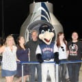 Photograph by Linda KC Reynolds Roberta Thompson, Kasiri Landon, Art Thompson, Kaboom, Emily Thompson and Jake Nelson have a little fun in front of the Red Bull Stratos Capsule during Aerospace Appreciation Night at JetHawk Stadium. Art Thompson of Sage Cheshire worked on designing, building and testing a similar capsule that brought Austrian skydiver Felix Baumgartner to the edge of space in 2012, where he jumped 127,852 feet and reached speeds of 843.6 mph. The event had more than 3 billion Google viewers. Landon and Nelson are pilots with Sky West Airlines and as youngsters, they learned to fly while soaring over the Antelope Valley.