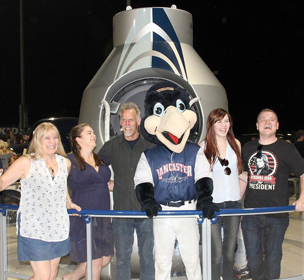 Photograph by Linda KC Reynolds Roberta Thompson, Kasiri Landon, Art Thompson, Kaboom, Emily Thompson and Jake Nelson have a little fun in front of the Red Bull Stratos Capsule during Aerospace Appreciation Night at JetHawk Stadium. Art Thompson of Sage Cheshire worked on designing, building and testing a similar capsule that brought Austrian skydiver Felix Baumgartner to the edge of space in 2012, where he jumped 127,852 feet and reached speeds of 843.6 mph. The event had more than 3 billion Google viewers. Landon and Nelson are pilots with Sky West Airlines and as youngsters, they learned to fly while soaring over the Antelope Valley.