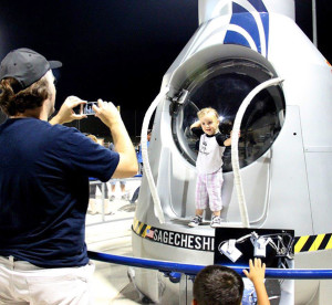 Photograph by Linda KC Reynolds Pop that pose -- A little girl gets her photo taken by her father during Aerospace Appreciation Night at Jethawk Stadium on the Red Bull Stratos Capsule. Art Thompson of Sage Cheshire, designed and built the capsule, and hopes that displaying it, and the JetHawk Baseball Bullpen helmet car, will help encourage youngsters to study hard to become engineers, scientist, pilots and astronauts.