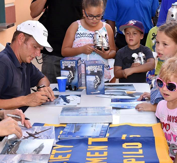Photograph by Shawna Nelson Kids of all ages collect photographs autographed by test pilots at the annual Aerospace Appreciation Night at JetHawk Stadium. The 2016 honor recognized Art and Roberta Thompson of Sage Cheshire for their work on the Red Bull Stratos project.