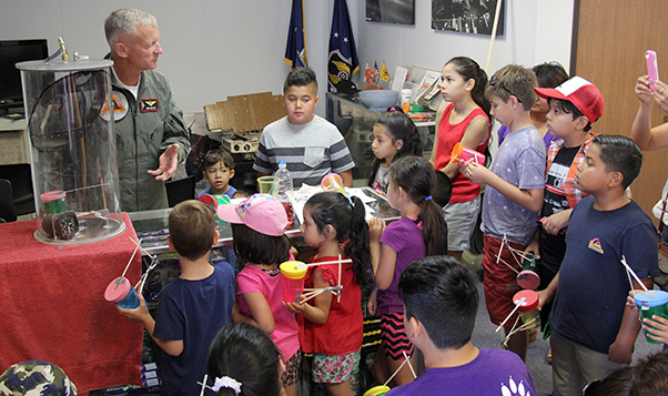 Photograph by Linda KC Reynolds Not too young to learn -- Northrop Grumman B-2 test pilot Don Weiss teaches children attending the Junior Test Pilot School Summer Museum Program how to build a working altimeter using simple supplies. Weiss also taught children about an aneroid; the importance of a Kollsman Tab, Boyles Law and Charles’ Law. The free summer programs runs through Aug. 3 at the Blackbird Airpark in Palmdale.