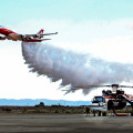 Photograph by Linda KC Reynolds A Boeing Global SuperTanker dumps water and retardant over a 4,000 foot long test grid at Gen. William J. Fox Airfield while crew members of a Skycrane watch. More tests are scheduled to test for accuracy of dispersed drops.