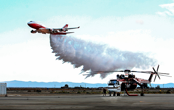 Photograph by Linda KC Reynolds A Boeing Global SuperTanker dumps water and retardant over a 4,000 foot long test grid at Gen. William J. Fox Airfield while crew members of a Skycrane watch. More tests are scheduled to test for accuracy of dispersed drops.