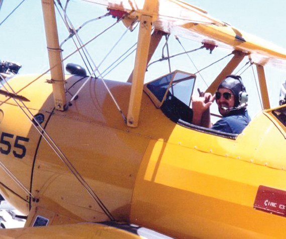 Bob Alvis gives the “hang loose” sign in a Stearman Biplane on the runway in Santa Monica. On a long ago Fourth of July, owner Dr. Randy Sherman gave Alvis a ride and let him pilot it. (Courtesy photograph)