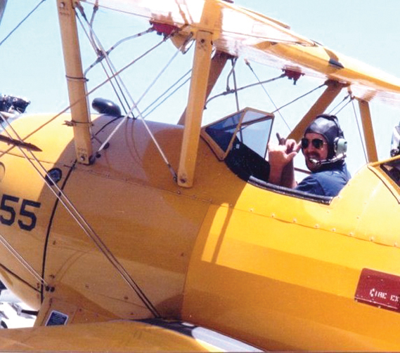 Bob Alvis gives the “hang loose” sign in a Stearman Biplane on the runway in Santa Monica. On a long ago Fourth of July, owner Dr. Randy Sherman gave Alvis a ride and let him pilot it. (Courtesy photograph)