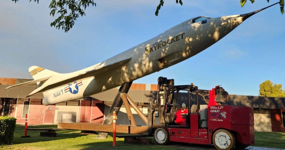 The Douglas D-558-II Skyrocket at Antelope Valley College on Friday night, with the specialty lifting fixture attached. The brown metal fixture was custom fabricated by Coast Machinery Movers to allow the Versalift to move the airplane. Steel plates were laid at the rear of the Versalift to protect the grass from the heavy equipment. The plane will be refurbished and reinstalled in a new location after campus construction is finished. (Photo by Lisa Kinison)