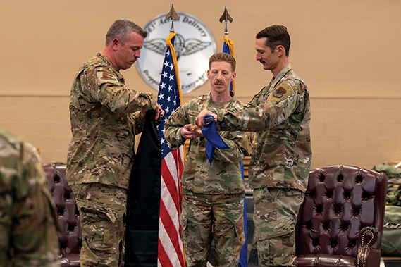 U.S. Air Force Lt. Col. Aaron Knight, former 355th Operations Support Squadron commander, right, rolls the 355th OSS guidon as Lt. Col. Patrick Chapman, 355th Operations Group deputy commander, left, prepares to sheath it during the 355th OSS inactivation ceremony at Davis-Monthan Air Force Base, Arizona, April 3, 2025. The sheathing of the guidon symbolized the inactivation of the squadron. (U.S. Air Force photo by Senior Airman Devlin Bishop)