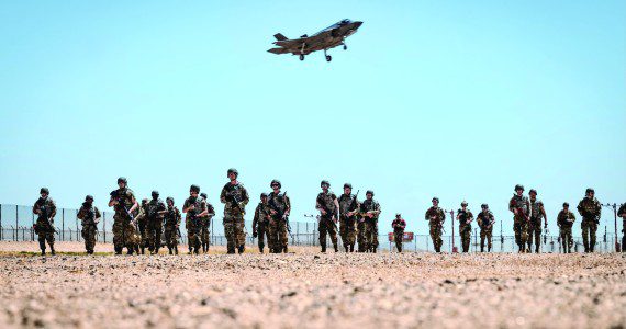 U.S. Air Force Airmen attending the John J. Rhoades Airman Leadership School march to a forward operating point near the flightline as an F-35A Lightning II prepares to land, May 2, 2025, at Luke Air Force Base, Arizona. Ready Airman Training, a day of hands-on training in which all ALS students participated, included tactical combat casualty care, runway repair, and clearing buildings. The students, drawn from various career fields, are preparing to become future non-commissioned officers in the Air Force. (U.S. Air Force photos by Airman 1st Class Belinda Guachun-Chichay)
