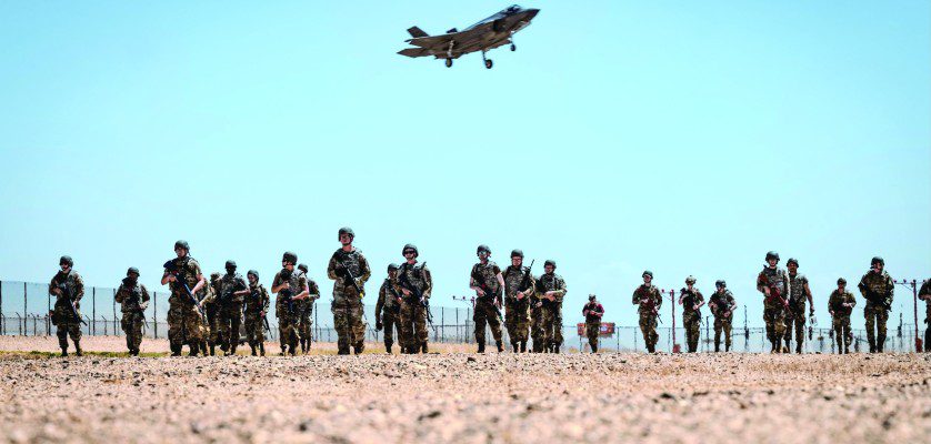 U.S. Air Force Airmen attending the John J. Rhoades Airman Leadership School march to a forward operating point near the flightline as an F-35A Lightning II prepares to land, May 2, 2025, at Luke Air Force Base, Arizona. Ready Airman Training, a day of hands-on training in which all ALS students participated, included tactical combat casualty care, runway repair, and clearing buildings. The students, drawn from various career fields, are preparing to become future non-commissioned officers in the Air Force. (U.S. Air Force photos by Airman 1st Class Belinda Guachun-Chichay)