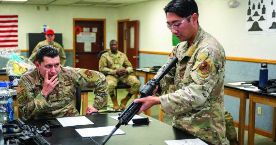 Members of the 56th and 944th Security Forces Squadrons watch as U.S. Air Force Staff Sgt. Casey Kaneshiro, 309th Aircraft Maintenance Unit weapons load crew member, disassembles an M4 carbine during a manipulation competition for National Police Week, May 14, 2025, at Luke Air Force Base, Arizona. Participants conducted timed disassembly, reassembly, and function drills of the M4 carbine and M17 pistol for a chance to win prizes.