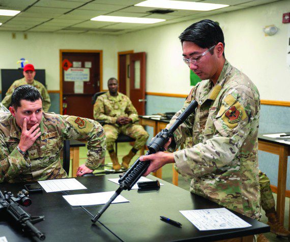 Members of the 56th and 944th Security Forces Squadrons watch as U.S. Air Force Staff Sgt. Casey Kaneshiro, 309th Aircraft Maintenance Unit weapons load crew member, disassembles an M4 carbine during a manipulation competition for National Police Week, May 14, 2025, at Luke Air Force Base, Arizona. Participants conducted timed disassembly, reassembly, and function drills of the M4 carbine and M17 pistol for a chance to win prizes.